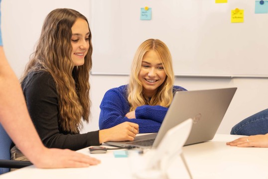 Zwei Mitarbeitende vor einem Laptop