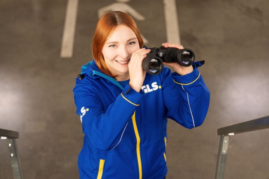 Employee has binoculars in her hand and smiles at the camera
