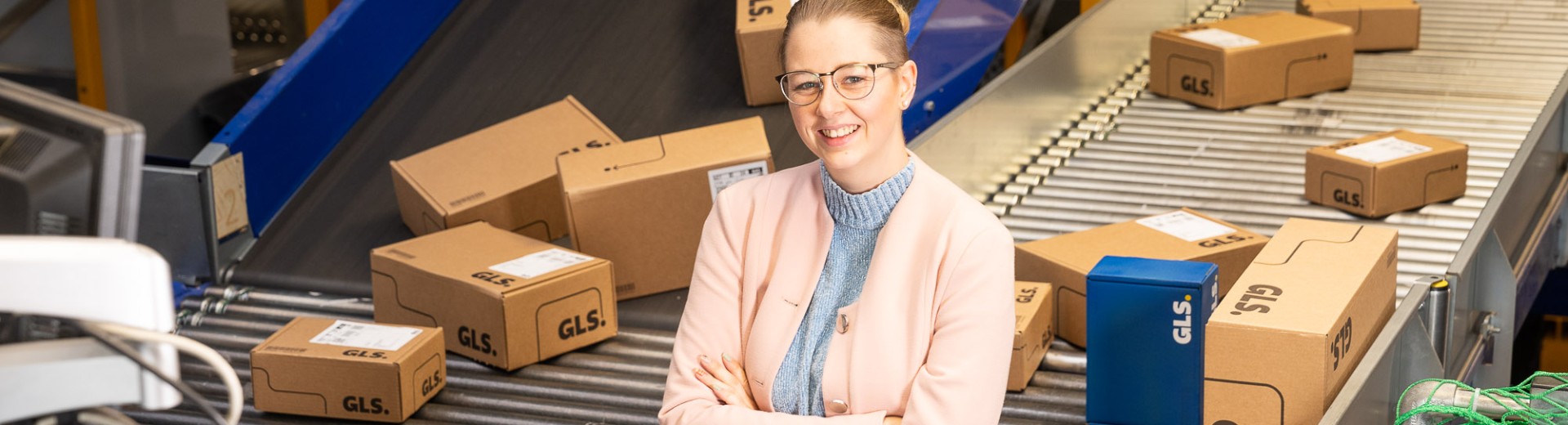 Young manager stands in front of a conveyor belt system with many packages