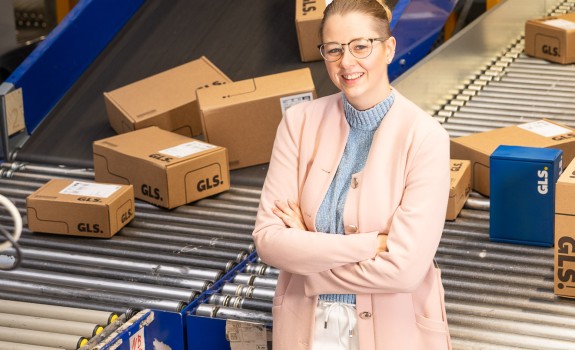 Young manager stands in front of a conveyor belt system with many packages