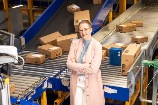 Young manager stands in front of a conveyor belt system with many packages