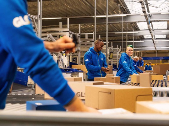 Employees work together in the warehouse and place packages on the conveyor belt